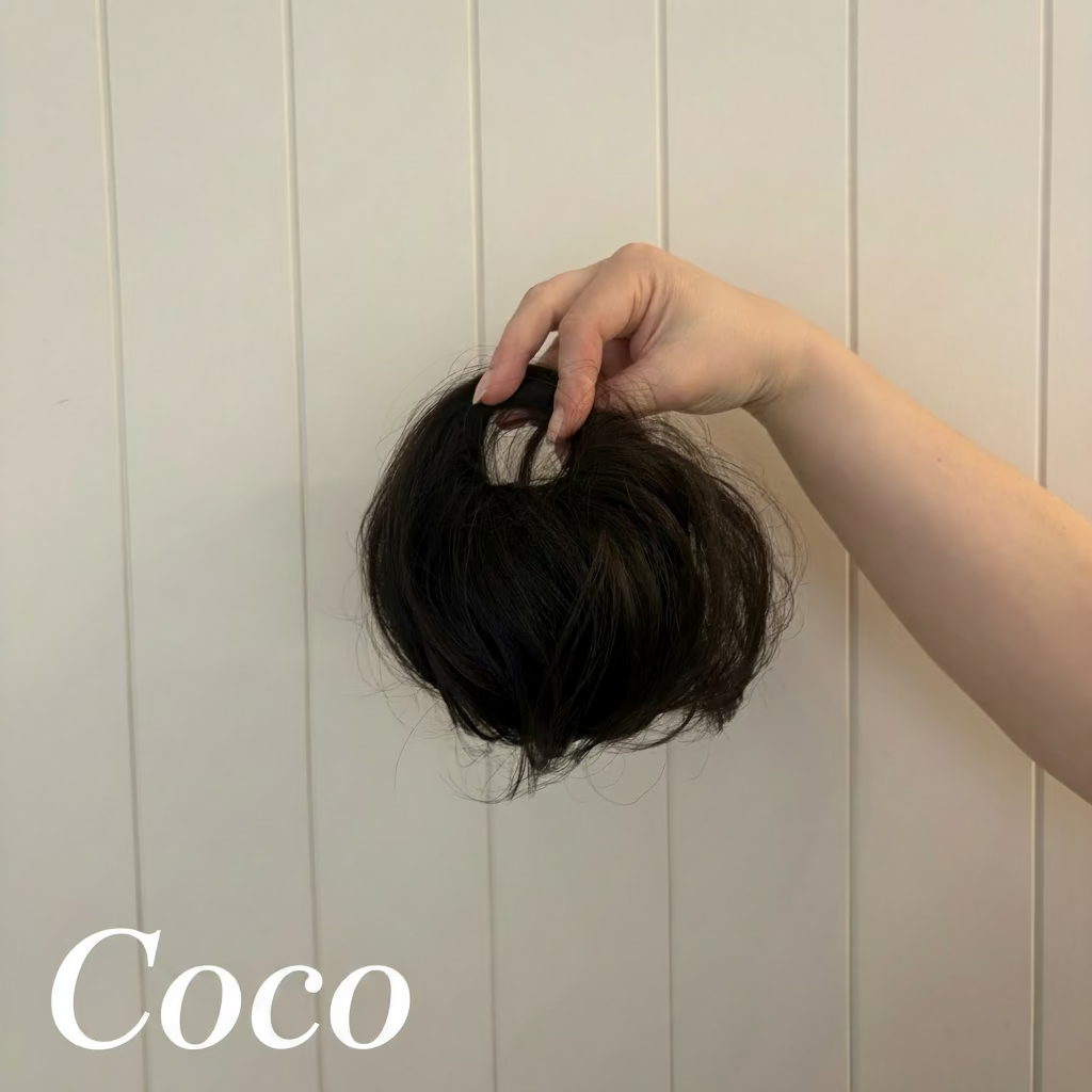 Hand holding a hair bun against a white paneled wall
